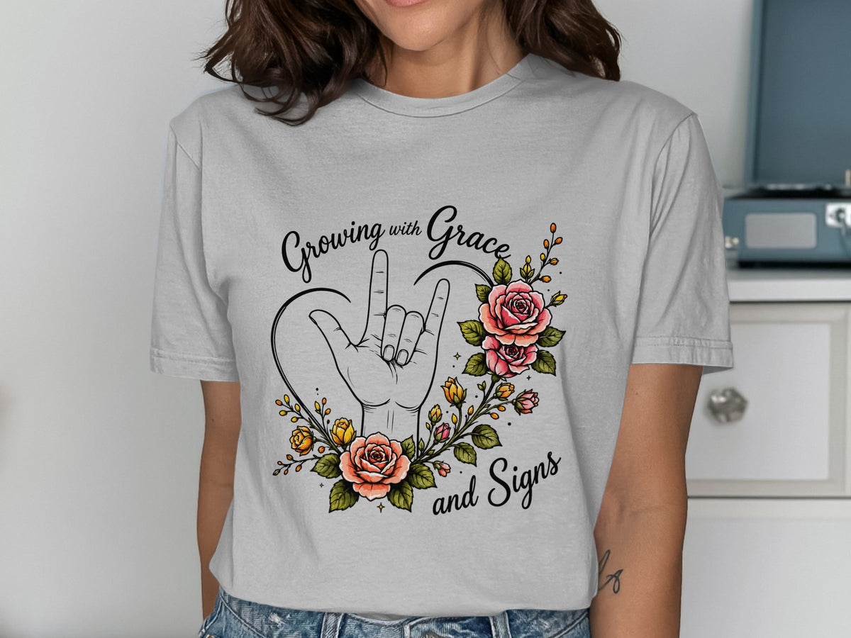 T-shirt graphic with "Growing with Grace and Signs" and a hand making a sign language gesture surrounded by flowers.