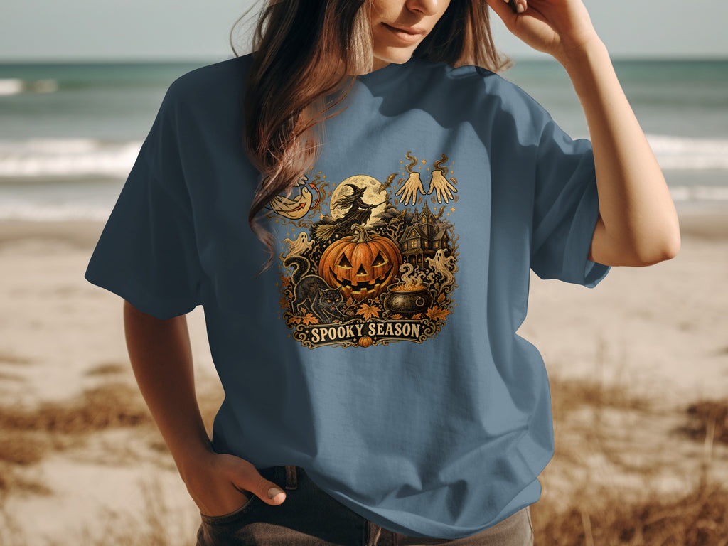 Blue t-shirt with Halloween graphic featuring a witch, pumpkin, haunted house, and "Spooky Season" text.