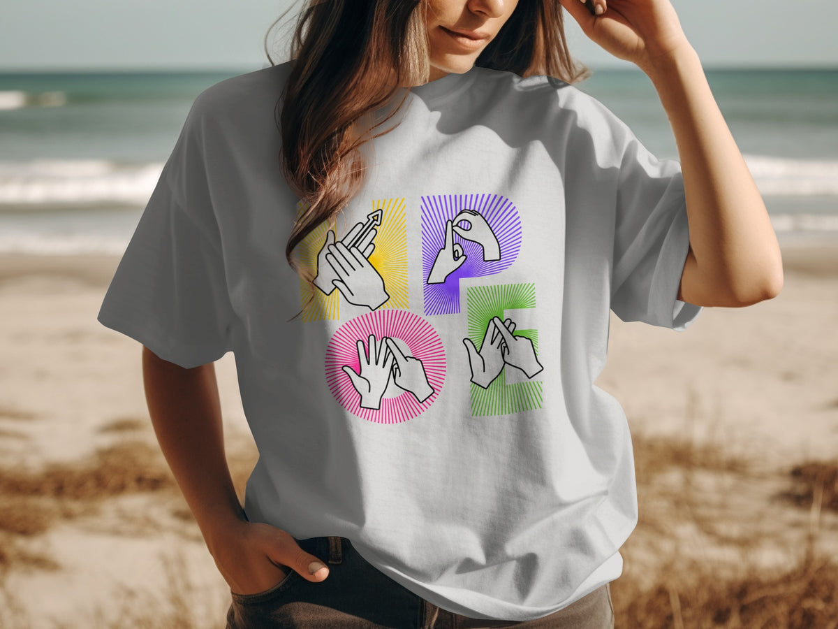 T-shirt with colorful hands forming letters, on a beach background.