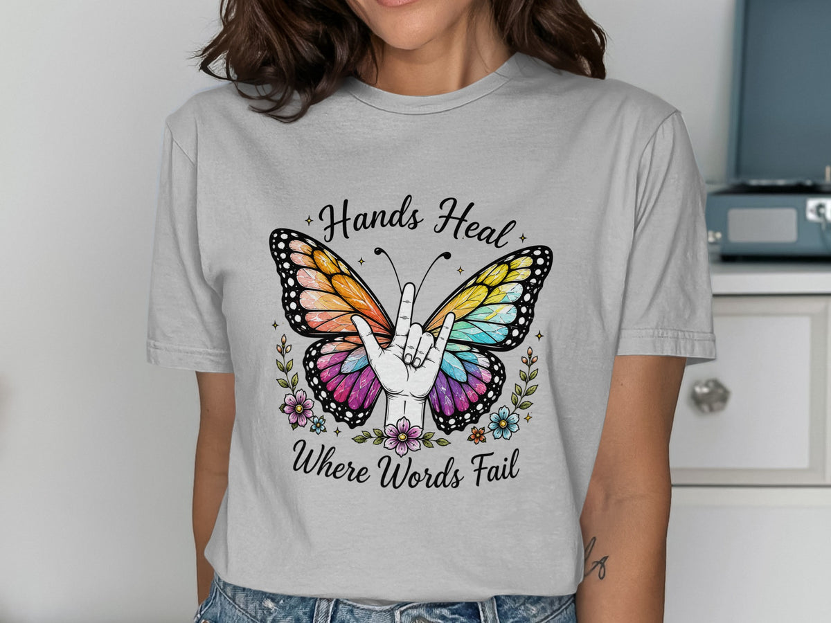 Gray t-shirt with a colorful butterfly, hand sign, flowers, and text "Hands Heal Where Words Fail".