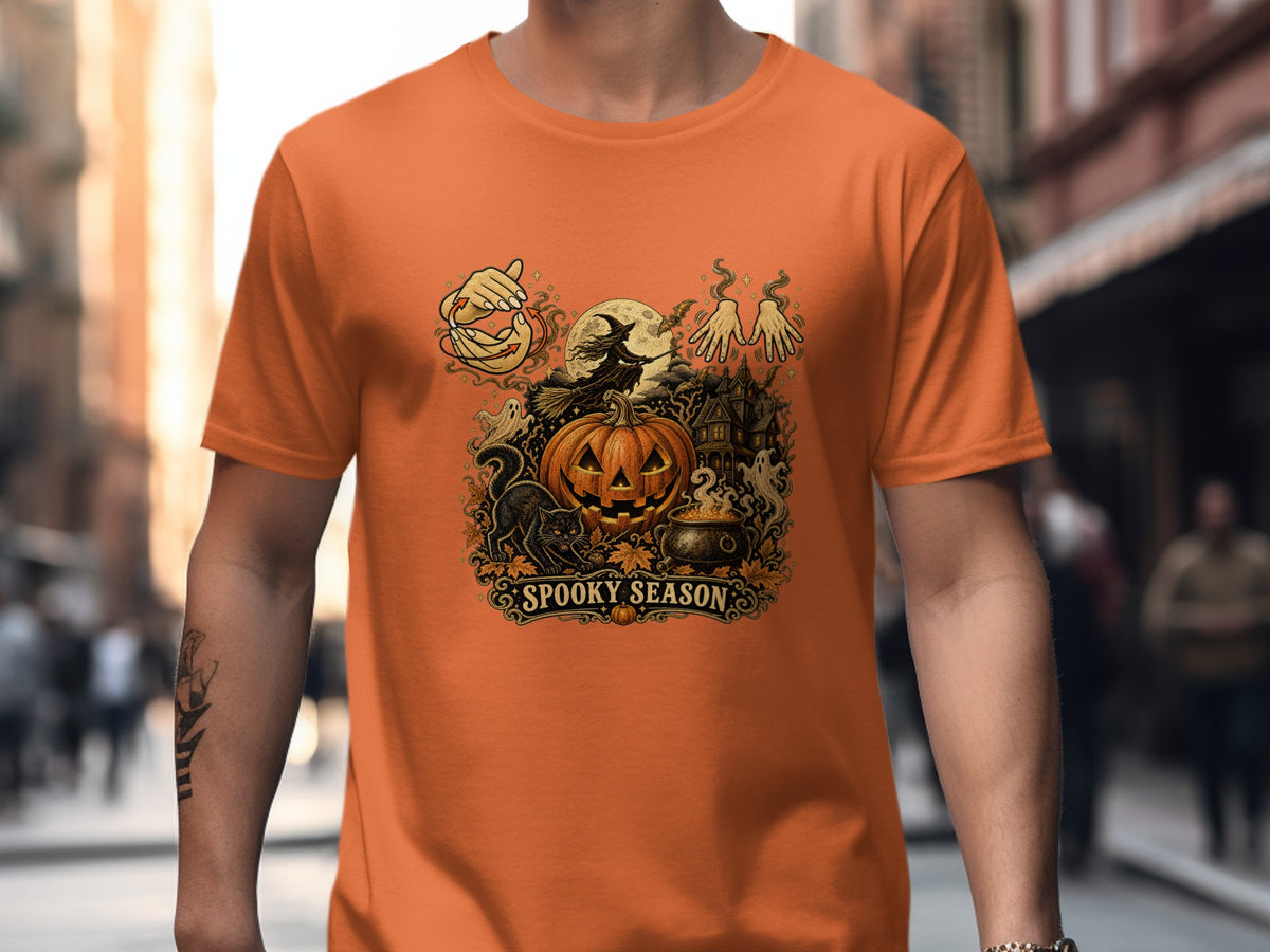 Orange t-shirt with a Halloween graphic featuring a pumpkin, witch, ghosts, and "Spooky Season".