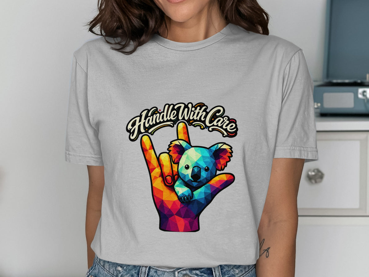 Graphic t-shirt with "Handle With Care" text and a colorful koala on a hand.