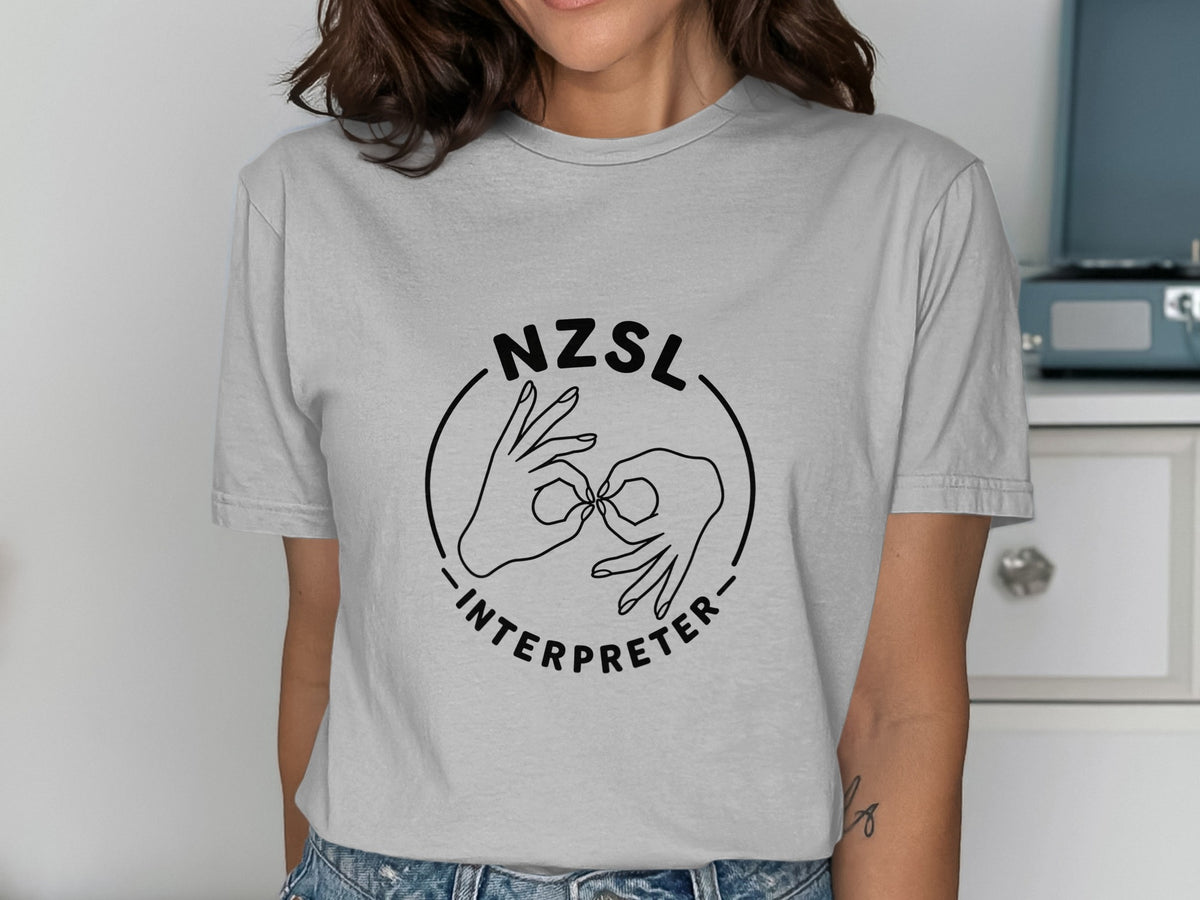 NZSL Interpreter graphic with hands signing on a light gray t-shirt.