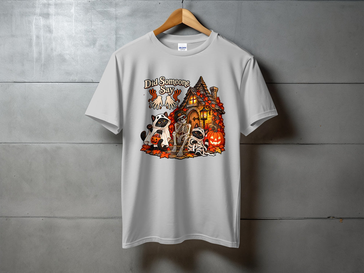White t-shirt with Halloween graphic: "Did Someone Say", cats, skeleton, haunted house, and pumpkins.