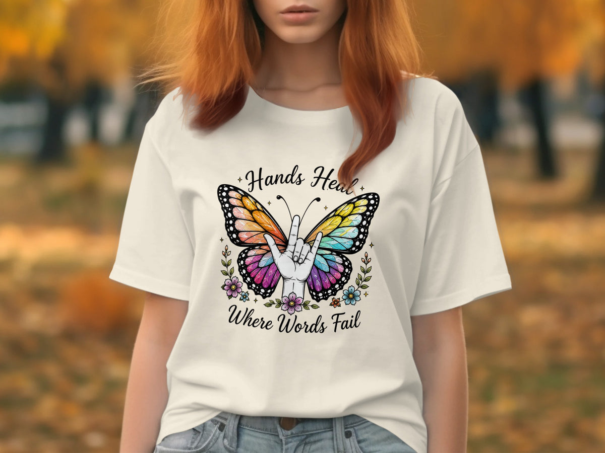 White t-shirt with "Hands Heal Where Words Fail" text and butterfly design.