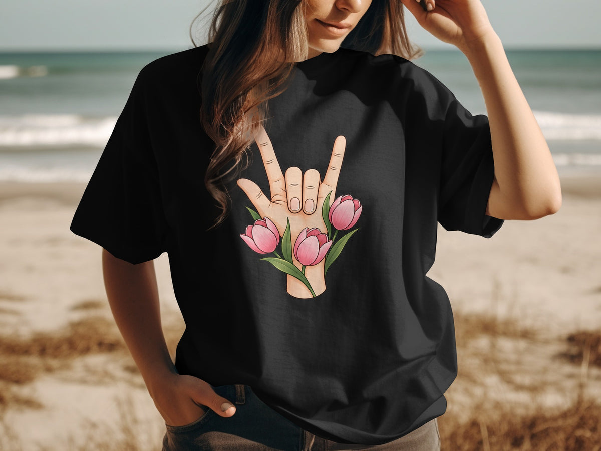 Black t-shirt with hand gesture and pink tulips graphic on beach background