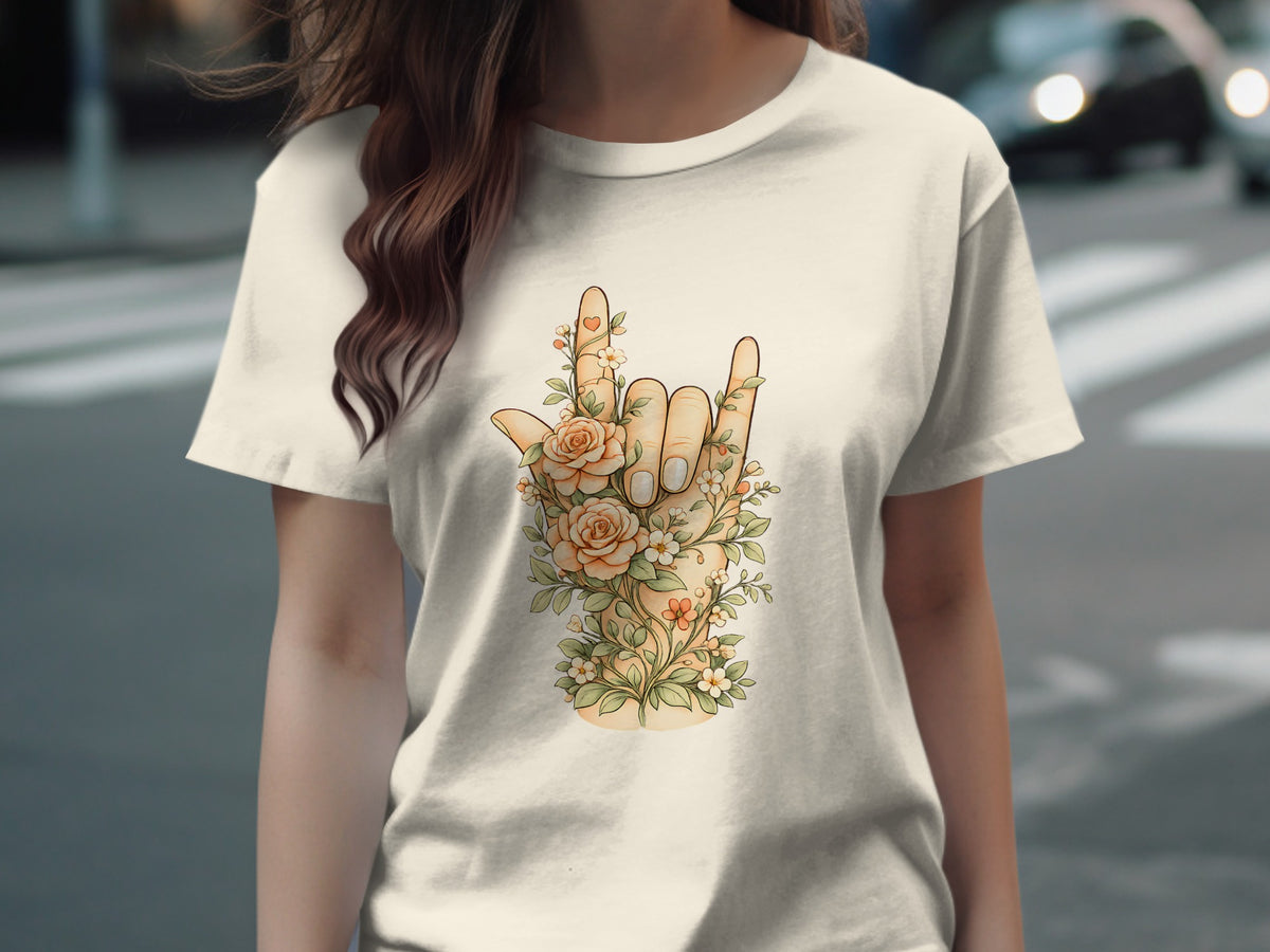 Hand with floral design making a rock on gesture on a light-colored t-shirt.