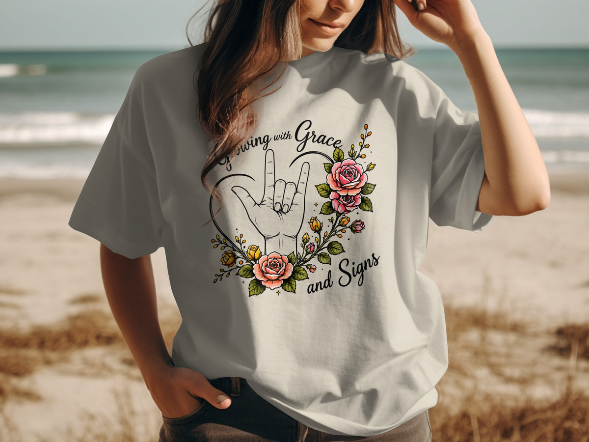 "Growing with Grace and Signs" text with ILY hand and floral wreath on shirt.