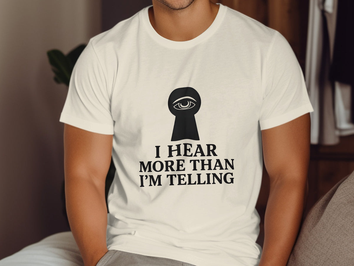 White t-shirt with black keyhole and eye graphic and text "I HEAR MORE THAN I'M TELLING."
