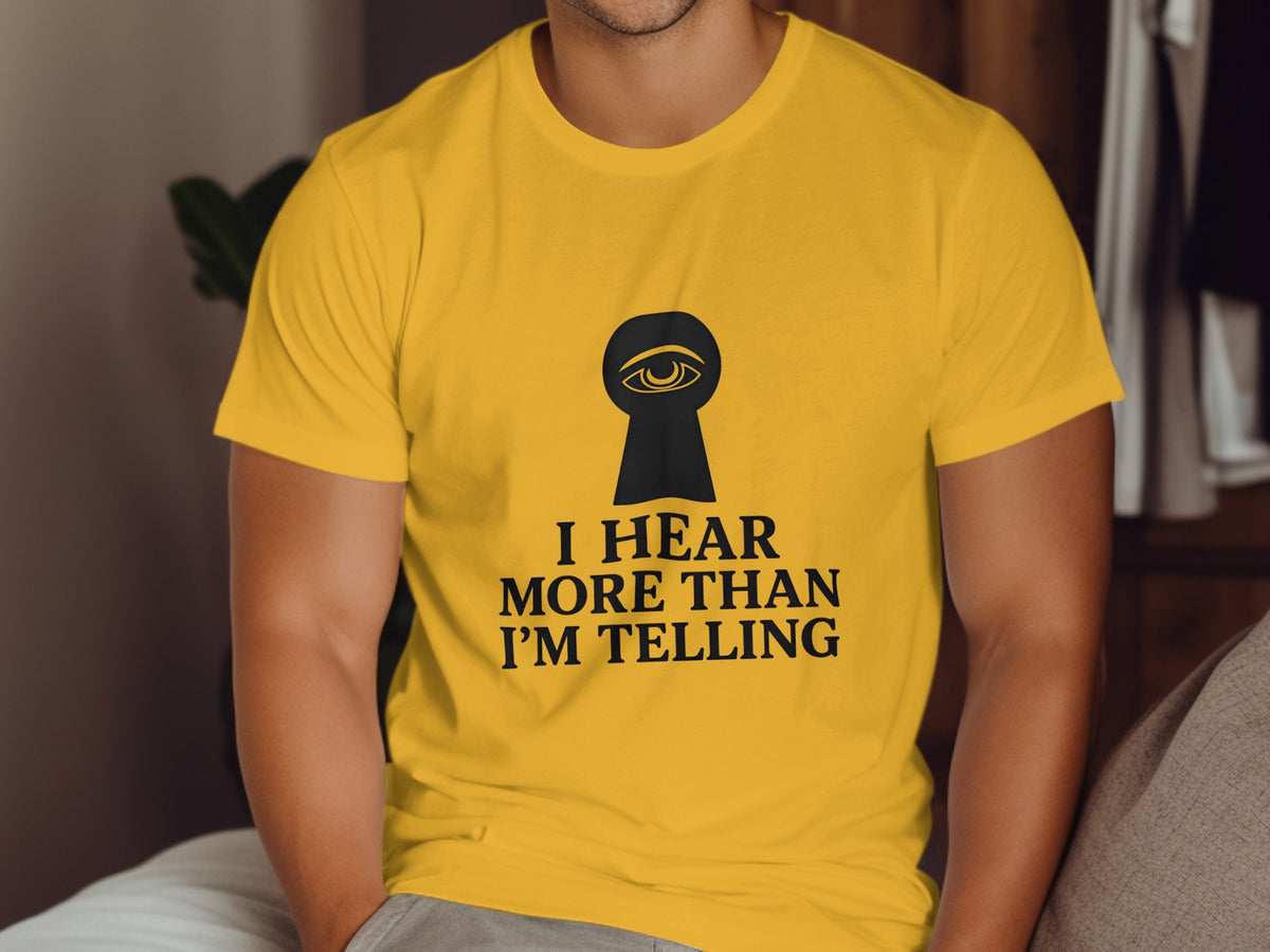 Yellow t-shirt with black keyhole eye graphic and text "I Hear More Than I'm Telling".