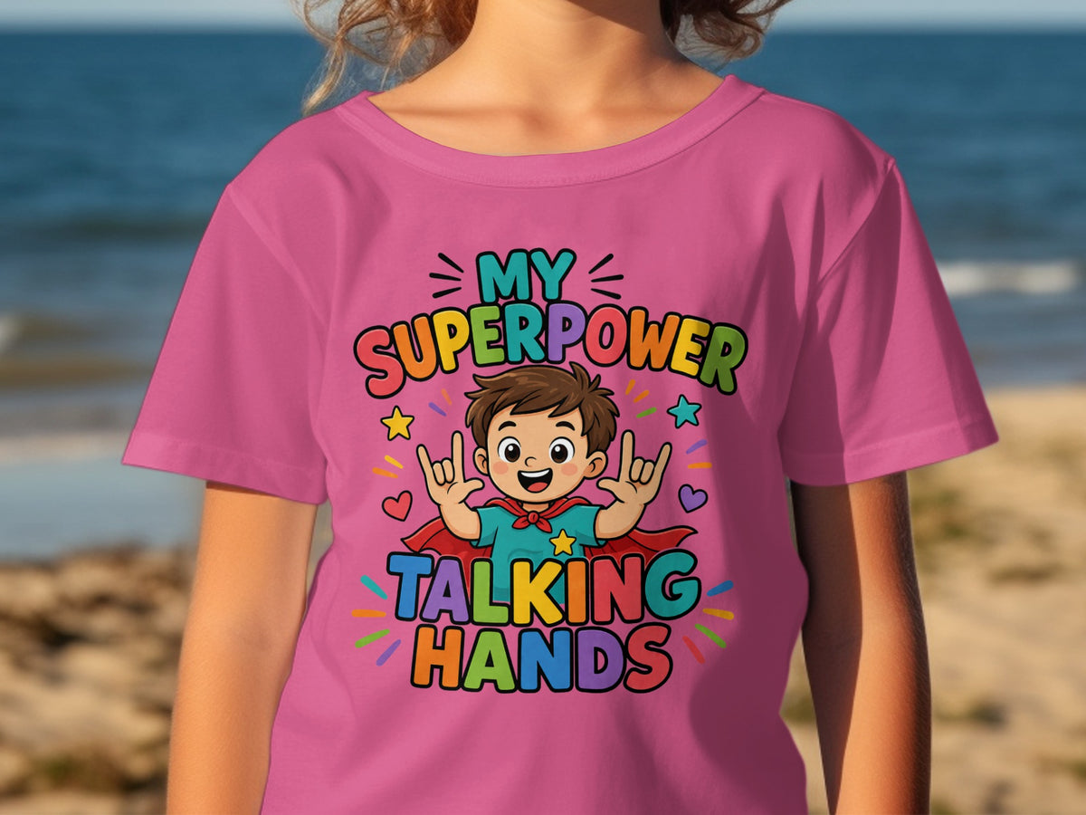 Pink t-shirt with cartoon boy wearing cape, stating "My Superpower Talking Hands."