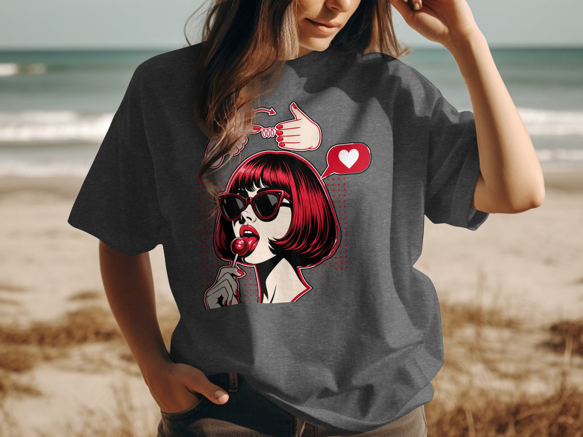 Pop art graphic on dark grey t-shirt of a woman with red hair and sunglasses eating a lollipop.