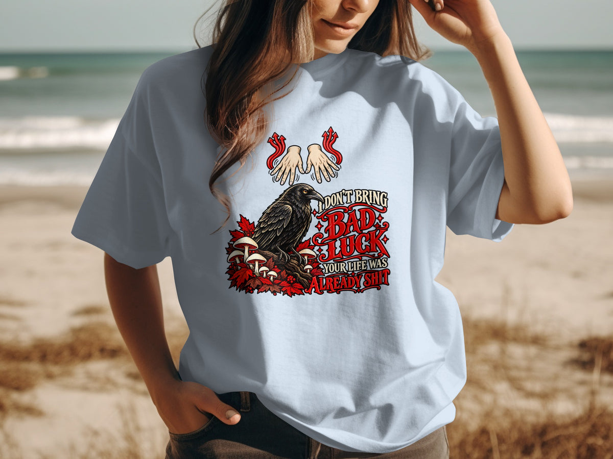 Light blue t-shirt with a raven, mushrooms, leaves, and text about bad luck.