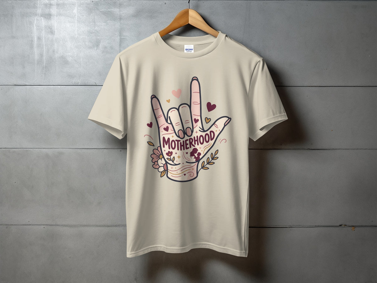 Cream t-shirt with "Motherhood" in a hand gesture graphic with hearts and flowers.