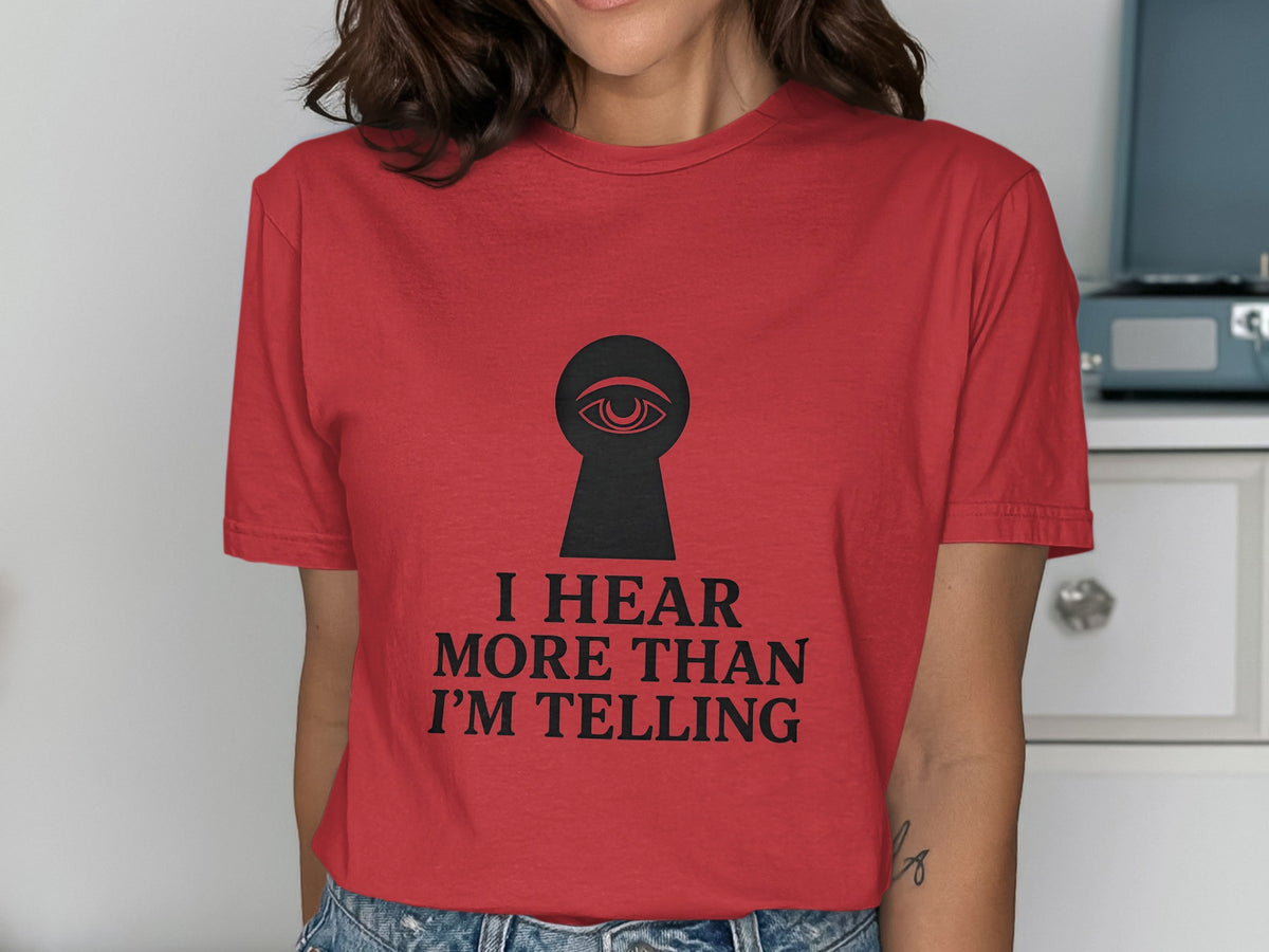 Red t-shirt with a black keyhole graphic containing an eye and text "I HEAR MORE THAN I'M TELLING".