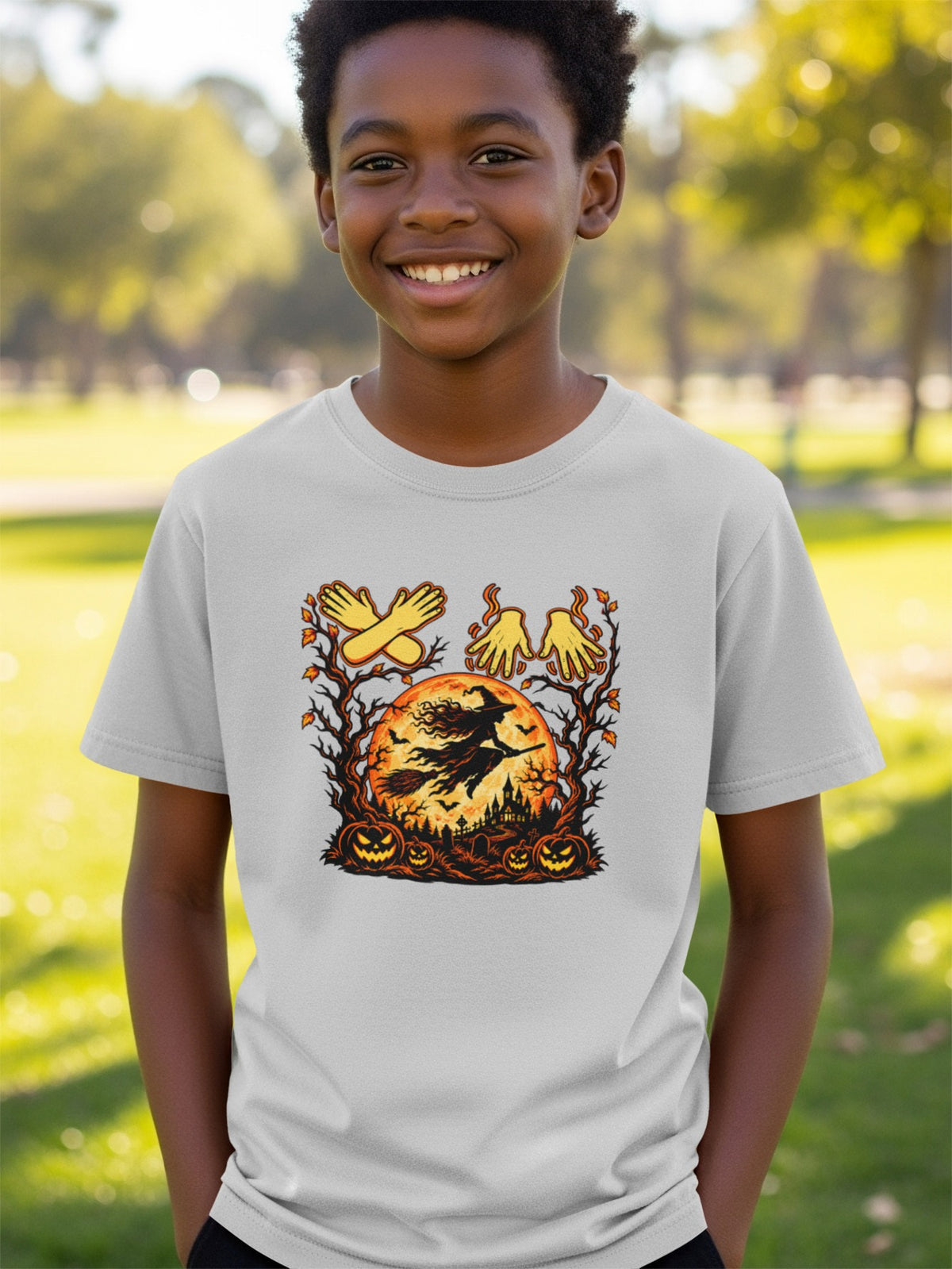 Halloween t-shirt graphic with witch, pumpkins, graveyard, and hand shapes.