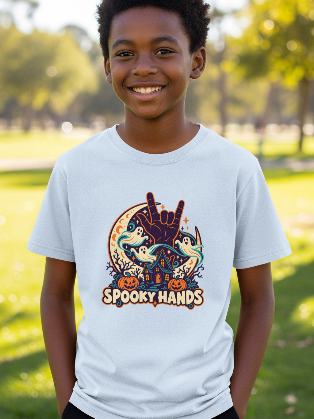 T-shirt with "Spooky Hands" Halloween graphic featuring a rock-on hand gesture, ghosts, pumpkins, and a haunted house.