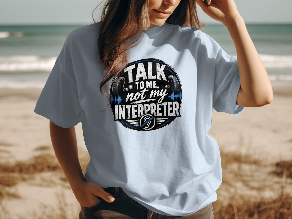 Light blue t-shirt with "Talk To Me, Not My Interpreter" text and headphones graphic.