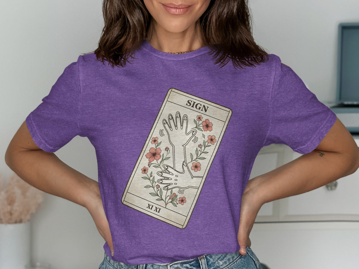 Purple t-shirt with a tarot card design featuring hands and flowers.