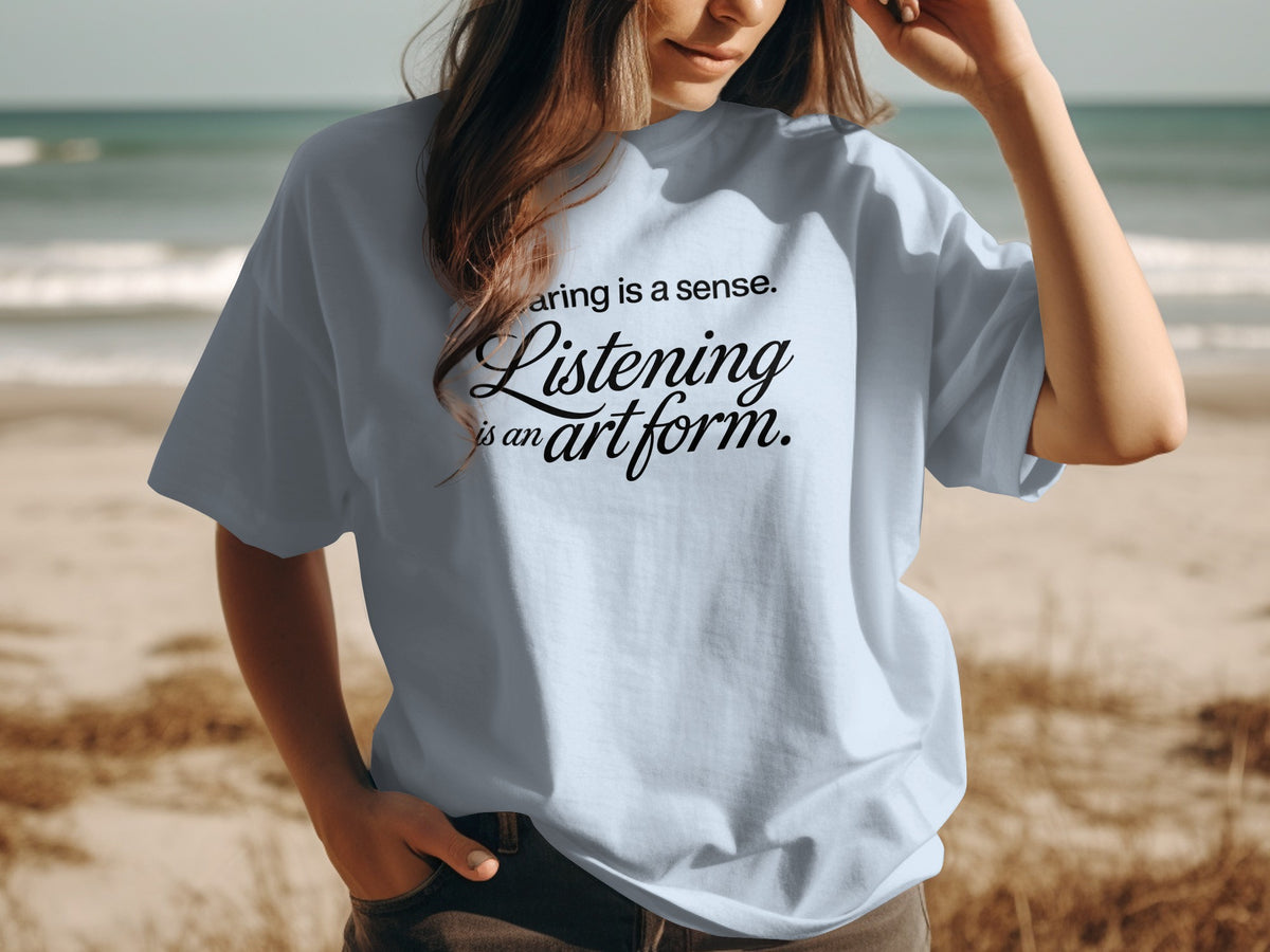 Light blue t-shirt with "Hearing is a sense. Listening is an art form." printed on it.